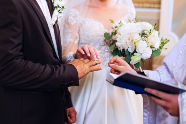 Gelin ve damat rahibin önünde yan yana durur ve alyanslarını takarlar.