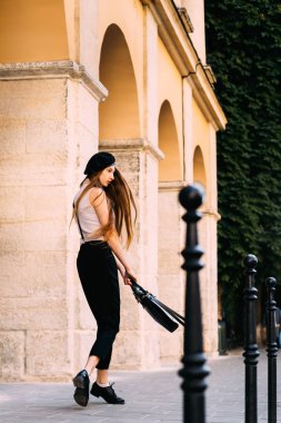 Siyah ve beyaz elbise giymiş ve siyah bir çanta ile bir bina çerçevede holding dışında ilginç bir kız kemerler