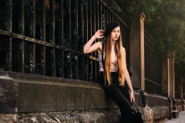 Eski bir çit arka plan üzerinde siyah beyaz giysili güzel kızı