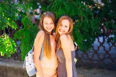 Onun en iyi arkadaşı gülümseyen kız omzuna bir sırt çantası ile kucaklar