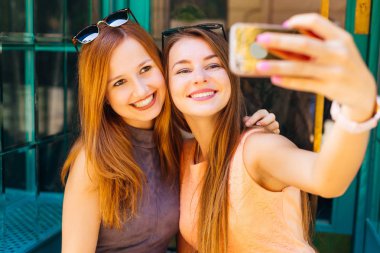 kendilerini kamera telefonda fotoğraf iki kız beyaz gülümsüyor