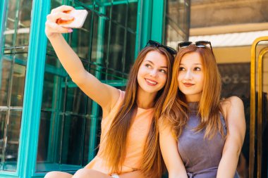 başlarına güneş gözlüklü şirin kızlar bir selfie cam kapı arka plan üzerinde olun.