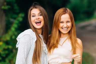 park arka plan üzerinde iki en iyi arkadaşlarından samimi gülümsüyor