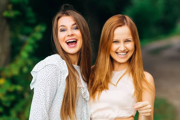 park arka plan üzerinde iki en iyi arkadaşlarından samimi gülümsüyor