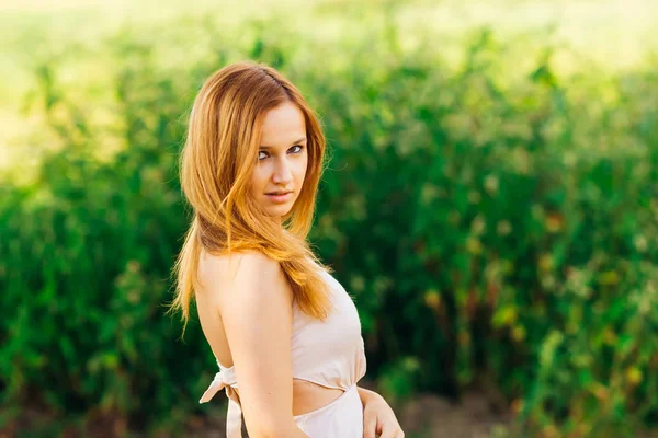 Yakın çekim yan ve seductively duruyor güzel bir makyaj kızla kamera lens görünüyor