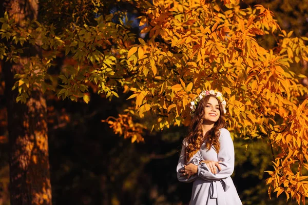 彼女の頭に花輪を捧げると幸せな女の子のクローズ アップや黄色い葉を持つ木の背景に閉じた彼女の目と笑顔 — ストック写真