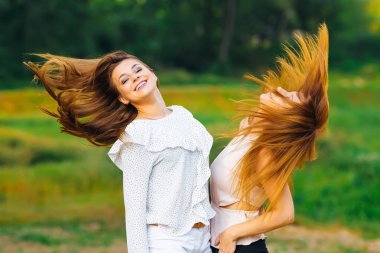 arkadaşlar stand tek tek ve salıncak saçlarını çim ve ağaçların arka planı