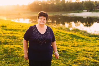 Gözlüklü yaşlı bir kadın bir akşam göl kıyısında bir dinlenme sahiptir