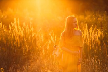 uzağa bakarak ve küçük çiçek elinde tutan yüksek çim arasında güzel kız 
