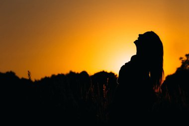 yüksek otların arasında akşam gökyüzü arka planı içten gülen bir kız silüeti