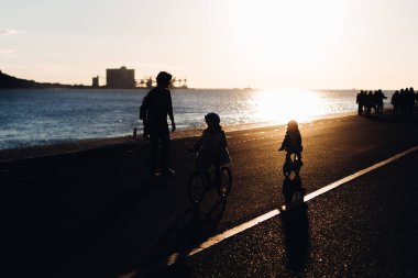 Lisbon, Portekiz - Ocak 2018 güzel gün batımı ve akşam nehir. siluetleri baba ve iki çocuk Bisiklet