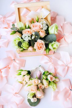 bir ahşap kutu gül, üç yaka çiçeği ile çok sayıda pembe yay üstten görünüm