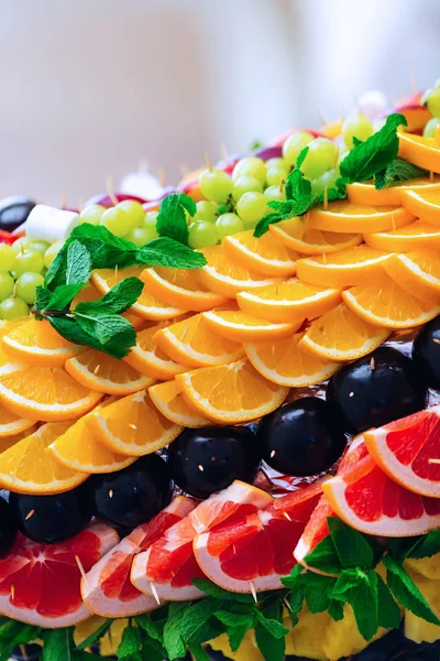 slices of orange and grapefruit as well as plum and grapes beautiful design and decorated with mint leaves