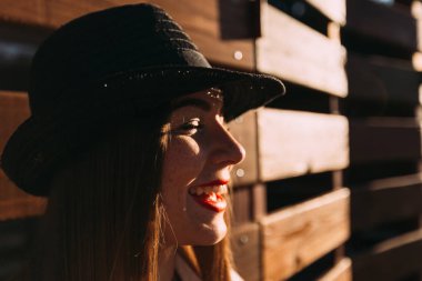 bir kızın yüzü çilli gözleri kapalı ve bir ahşap çit ve sevimli gülümseme eğildi, yakın çekim profil