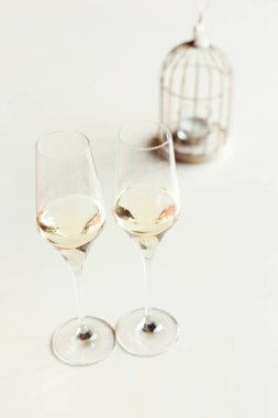 Masanın üzerinde beyaz bir masa örtüsü ve yanında mum olan bir kafes olan iki kadeh şampanya.