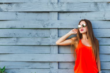 şık kız kırmızı bluz ve güneş gözlüğü ahşap bir çit için eğildi