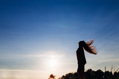 siluet eğlenceli doğa üzerinde olan bir kadının. o uzun saçları dalgalar