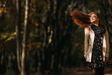 Neşeli kız açık havada doğanın keyfini. Kızdırma saç sallayarak ile güzel sonbahar saç modeli. Hareketli fotoğraf.