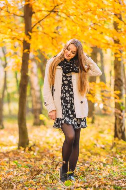 Sevimli ve seksi genç kadın güneşli sonbahar gününde Park'ta yürüyordunuz. Canlı renkler, arka yaktı, doğal ışık.