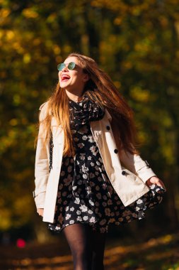 Neşeli kız kızdırma saç sonbahar parkta güneşli günü çalışacak duygusal gülümseme ile elbise ve beyaz önlük sallayarak ile. Hareketli fotoğraf.