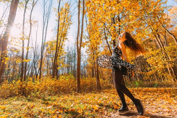 豪華な飛行に手を振っている輝きは長い髪の遊び心のあるスリムな若い女の子のドレス回転し周り踊りと晴れた日に秋の公園で楽しんでいます モーションの写真 — ストック写真