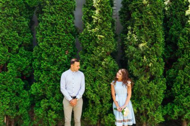 Aşık çift yeşil ağaçlar arasında stand ve birbirinize bakın ve gülümseme