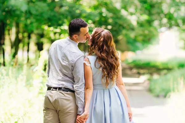 男と女が手を繋いでいると 公園の背景にキスのカメラに戻ってスタンドします — ストック写真