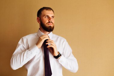 Damat şık sakallı kravat duvar arka planı ayarlar ve yan görünüyor