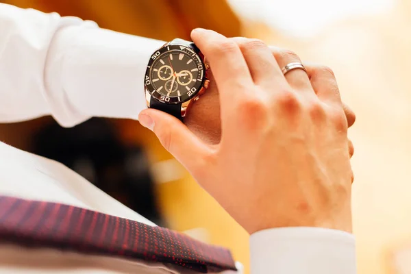 stylish and modern watch on the groom\'s hand who looks at watch dial