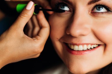 güzel bir gülümseme ile gelinin yüzü Close-up. Makyaj sanatçı uygulanan maskara kirpik üzerinde