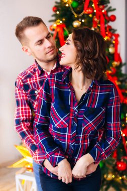 Adam kız arkadaşı arka hugs ve onlar Noel ağacı arka planı bakıyoruz