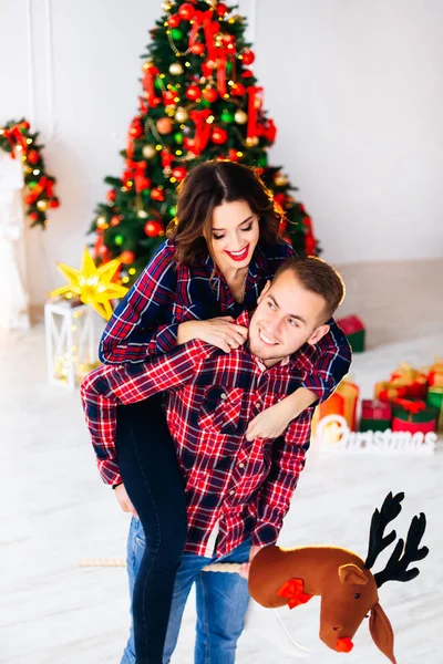 男が男に飛びついた少女と手で鹿の頭のモデルを保持し クリスマス ツリーの背景に微笑んだ — ストック写真
