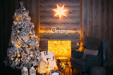 çelenk ile bir şömine ve rahat yumuşak koltuk bir battaniye ve yastık ile yakın güzel bir Noel ağacı
