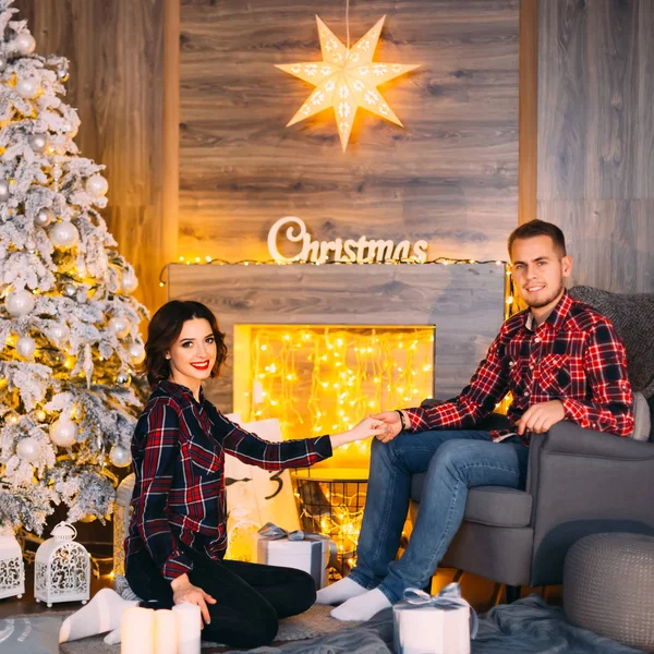 彼女の男は 椅子に座っている 居心地の良い部屋 クリスマス ツリーの近くで手を握りながら 少女は床に座ってください — ストック写真