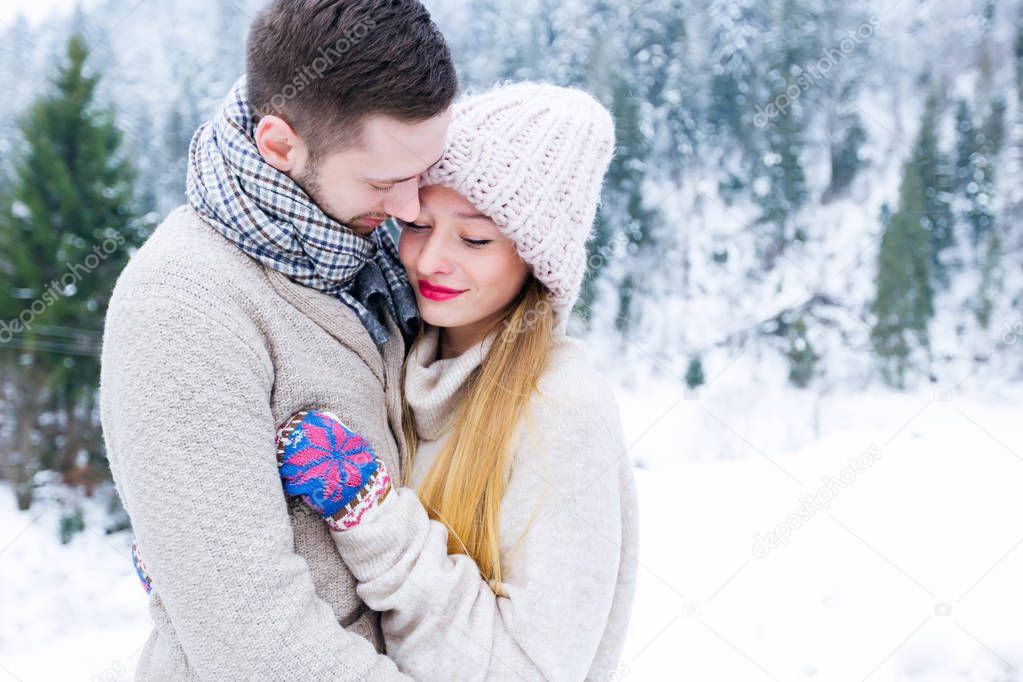 a close-up of a couple of love in sweaters that hug on the background of the winter mountains