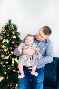 mutlu baba küçük kızı ellerinde tutan ve ona bir Noel ağacı fonunda bakar