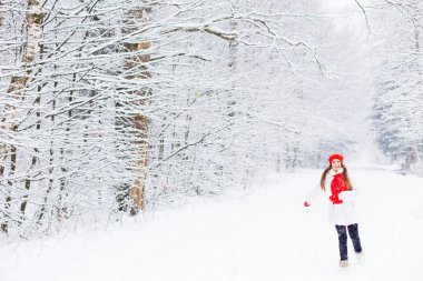 çalışan ve ağaçlar arka planı gülümseyen şık kış elbiseleri şirin bir kız karla kaplı