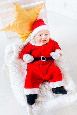 bir battaniye ve bir yıldız ve sevimli bir gülümseme şeklinde bir yastık üzerinde yalan Noel Baba kostümlü bir erkek çocuğun üstten görünüm
