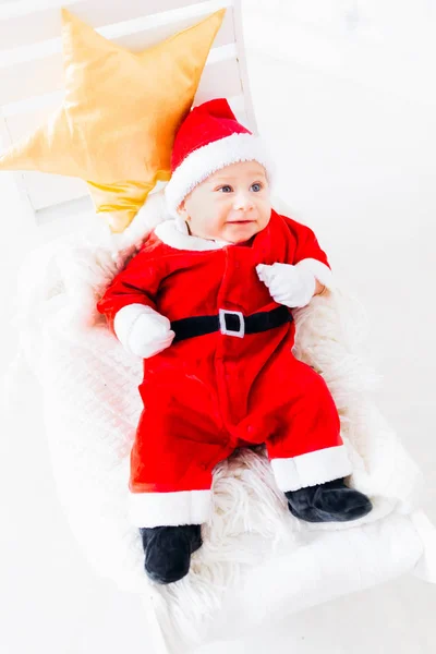 baby boy in a Santa Clause suit that lays on a blanket and pillow in the form of a star and looks aside