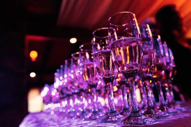 bir tabloda bir rahat restoranda masa örtüsü ile alkol ve üzerlerinde pembe ışık parlar ile şeffaf gözlük