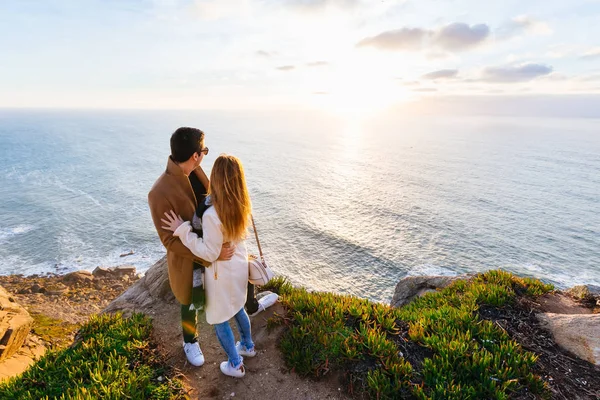 愛のカップルお互いを受け入れて 立ってカメラをバックアップします 彼らは岩の海岸に立って 海と夕日を見て — ストック写真
