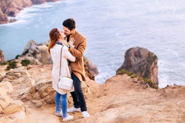 adam ve kız birbirlerine ve taşlı akşam okyanus kıyısında öpmek istiyorum kucaklayan