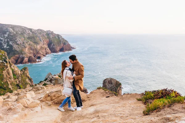 男孩和女孩想亲吻在岩石丘陵和傍晚海洋的背景 — 图库照片