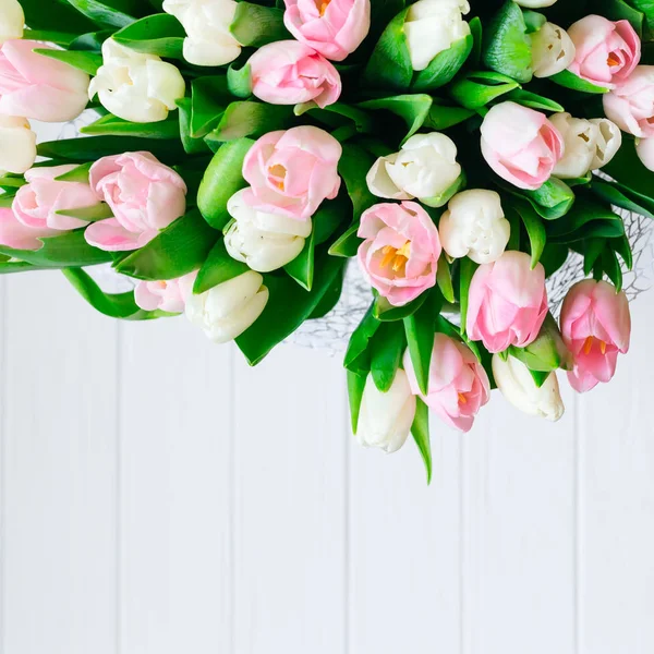 Spring color tulips in a bouquet with pink, white beautiful flowers isolated on wooden white background. Copy space, perfect for spring postcard.