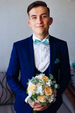 Mavi elbiseli güzel damat kamera lensi ve gülümsüyor görünüyor. o şık düğün buket tutar