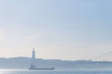 Yukarıdaki river Tagus hafif bir sis olduğunu Lizbon Portekiz - 20 Ocak. büyük bir gemi ve ters Bankası ve köprü siluetleri