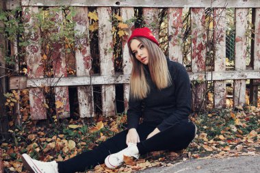 Kırmızı şapkalı serin trendy kız bir çit duvara eğilir. Hippi tarzı. Gençlik moda.