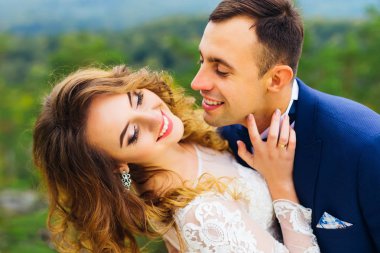 Gelin sırt ve gülümsüyor bükülmüş ve damat onu öpmek istiyor