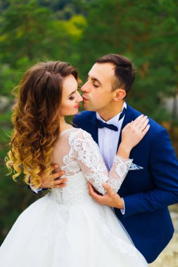 Gelin tekrar fotoğraf duruyor ve damat onu kucaklayan ve öpmek ister