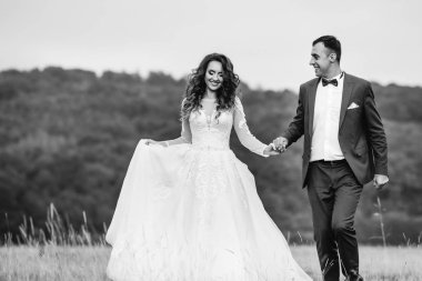 Yeni evliler el ele tutuşup arka planı orman çim üzerinde yürümek